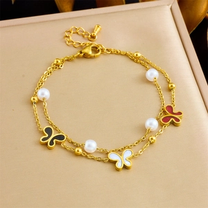 Dettaglio macro del bracciale a doppio strato dorato con farfalle smaltate e perle