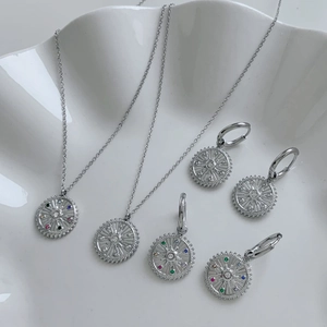Silver retro sun pendant necklace and earrings set with colorful crystals in ceramic tray