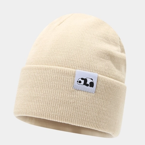 Close-up of beige knit beanie with a woven panda patch and detailed ribbed texture