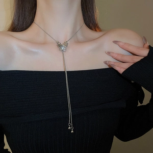 Detail of silver butterfly pendant necklace with elegant long fringe tassels on model