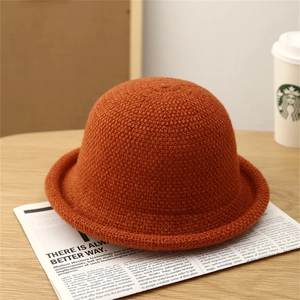 Close-up of orange knitted bucket hat showing rich woven texture and rolled brim detail