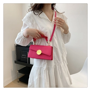Gros plan d'un sac à main rose fuchsia avec boucle dorée et poignée plissée