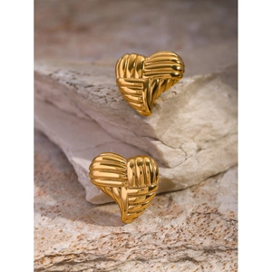 Detail of 18k gold heart earrings with textured surface resting on a natural stone