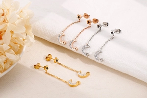Detail of star and moon dangle earrings in gold, silver, and rose gold with zircon stones