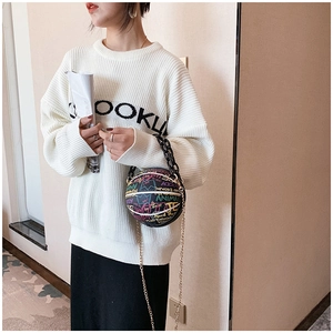 Detail shot of a black basketball-shaped handbag with colorful graffiti and chain strap