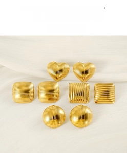 Detailed view of geometric gold earrings with textured stripe patterns on white silk cloth