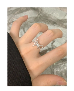Close-up of a silver irregular twisted bow ring worn on a finger for a minimalist look