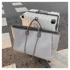 Macro shot of grey large tote bag with woven texture leaning on suitcase in sunlight