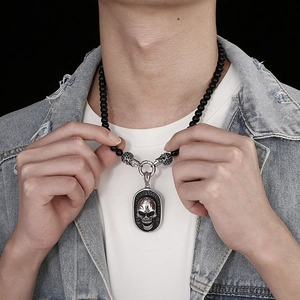 Detail of silver skull pendant necklace with black agate beads on male model