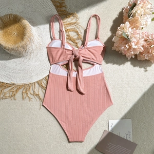 Détail d'un maillot de bain une pièce rose poudré côtelé avec nœud et découpe à la taille