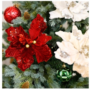 Close-up of red velvet poinsettia flowers with sequins on a decorated Christmas tree