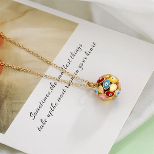 Macro detail of golden necklace with colorful enamel evil eye spherical pendant on card