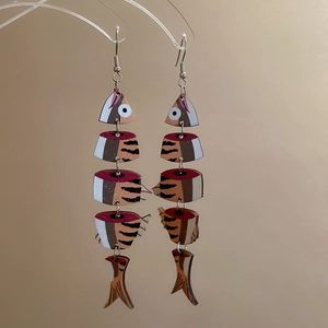 Macro shot of segmented fishbone drop earrings with vintage patterns on a display stand