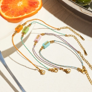 Close-up of colorful braided LOVE bracelets with gold accents and adjustable chains