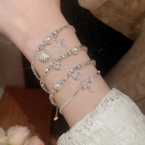 Vista dettagliata di bracciali in argento a strati con perle, stelle marine e ciondoli