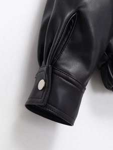 Détail du poignet d'une veste en similicuir noir avec boutons-pression argentés