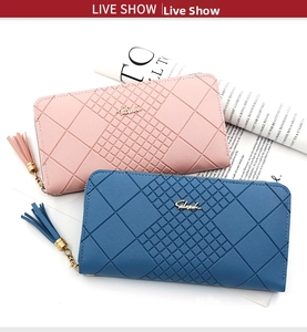 Close-up of pink and blue quilted long wallets with tassels on vintage magazine