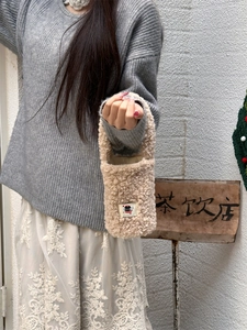 Close-up of soft beige plush teddy fleece handbag with cute cartoon patch detail