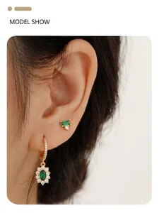 Close-up of S925 silver emerald flower earrings with gold finish and sparkling diamonds