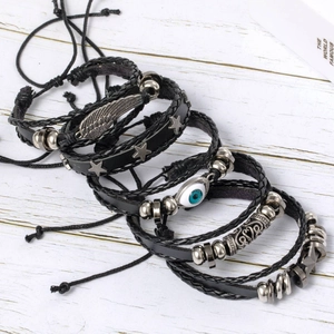 Macro detail of layered black braided leather bracelets with alloy beads and blue eye charm
