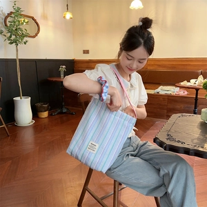 Détail du sac cabas en toile rayée et chouchou assorti sur une chaise de café