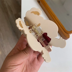 Detailed side view of a beige acrylic hair claw clip with wavy edges and metal spring