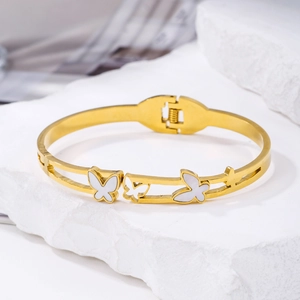 Macro shot of gold butterfly open bangle with white shell inlay and spring hinge detail