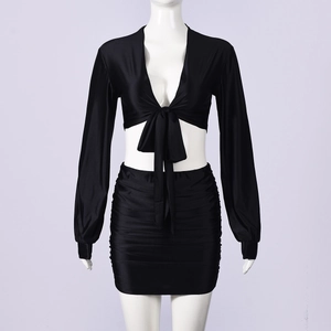 Detail of black long-sleeved tie-front crop top and bodycon skirt in satin fabric
