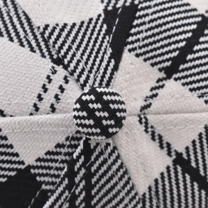 Close-up detail of black and white houndstooth pattern and top button on a baseball cap