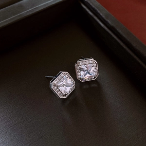Détail macro de boucles d'oreilles carrées halo en argent avec zircon dans un écrin de luxe