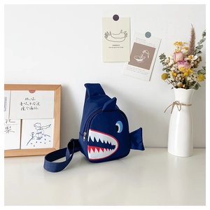 Detail of blue shark kids chest bag showing smooth fabric and 3D fin design on a desk
