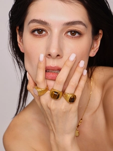 Close-up of gold rings with pink crystal and tiger eye stones on a model's hand