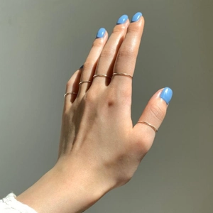 Detail view of five minimalist thin gold stackable rings worn by a model on fingers