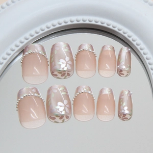 Floral cat eye press-on nails with pearls and translucent pink petals on a mirror surface