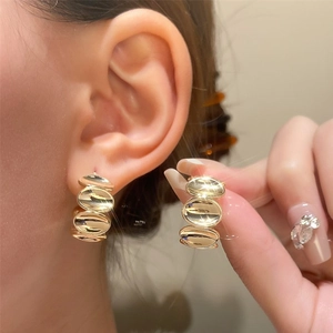 Close-up of elegant gold triple-layered oval drop earrings worn by a model in detail