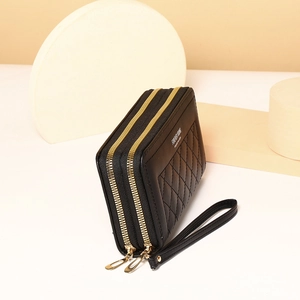 Detail of black quilted long wallet with dual gold zippers and wrist strap