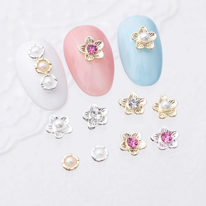 Floral nail charms with rhinestones and pearls on a white lace background