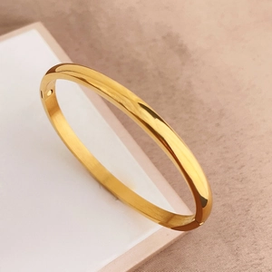 Dettaglio ravvicinato di un bracciale rigido in acciaio al titanio dorato lucido e spazzolato