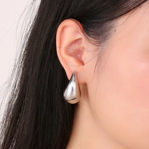 Detailed view of silver chubby teardrop earrings in polished stainless steel on model