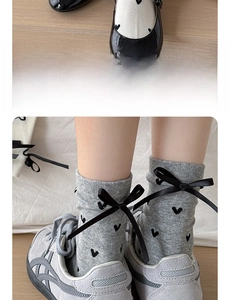Detail of sweet mid-calf cotton socks with heart prints and black bow accents