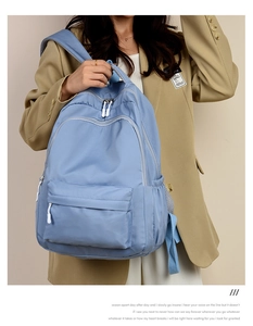 Detail of light blue high-capacity nylon backpack worn with khaki blazer for stylish look