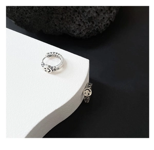 Macro shot of vintage silver smiley face earring with textured chain pattern details
