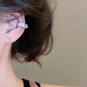 Detail of silver ear cuff with white enamel and sparkling zircon worn by a model