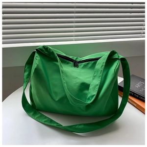 Detail of green nylon sports bag with double zipper and wide strap on white table