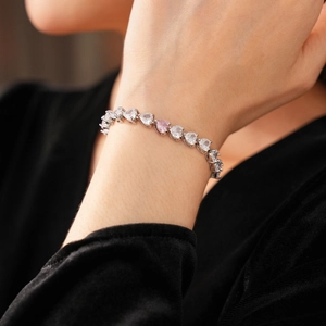 Gros plan d'un bracelet argenté orné de zircons roses et blancs en forme de cœur