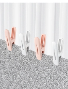 Detail of four large pink and white plastic laundry clips holding heavy grey fabric