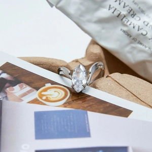 Detailed view of marquise-cut zircon ring with silver streamlined band on lifestyle background