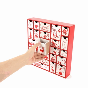 Hand pulling out the 12th drawer of a red and white wooden 24-day Christmas advent calendar