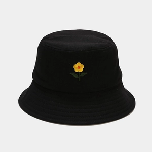Dettaglio di un cappello da pescatore nero in cotone con ricamo a fiore giallo e tesa cucita