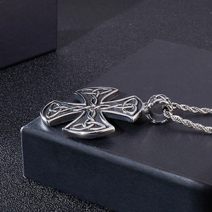 Macro detail of silver stainless steel Celtic knot cross pendant on a black stand